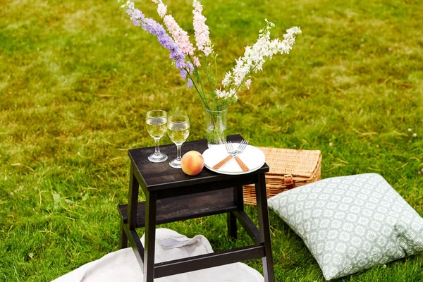 Kosz piknikowy, kwiaty i kieliszki do wina w parku — Zdjęcie stockowe