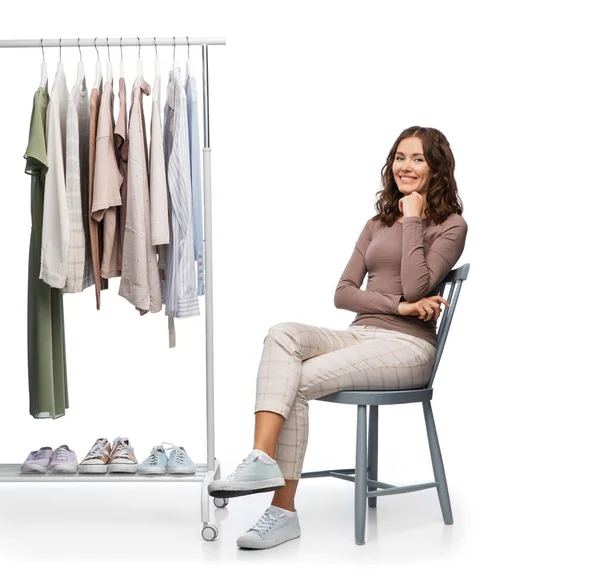 Assistente de loja feminino feliz com roupas no cabide — Fotografia de Stock