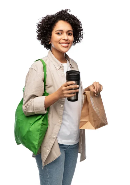 Donna felice con tazza termo, sacchetto di carta e shopper — Foto Stock