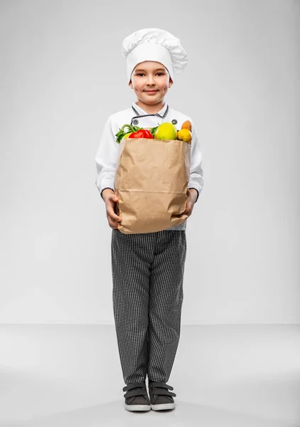 Boldog kisfiú szakácsok toque étellel zsákban — Stock Fotó