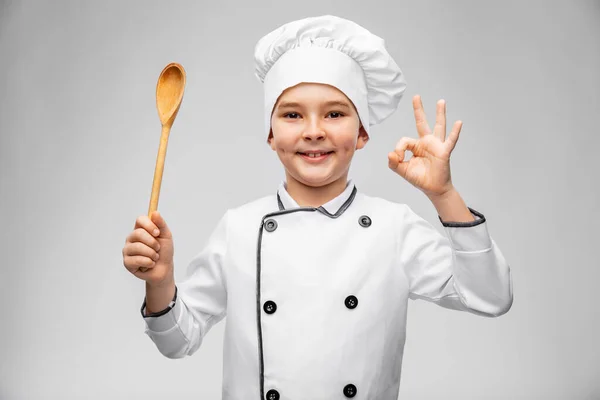 Glimlachende jongen in chef-koks toque met lepel tonen ok — Stockfoto