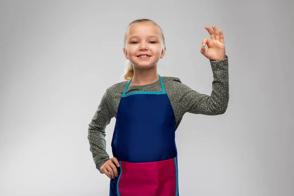 Smiling little girl in apron — Stock Photo, Image