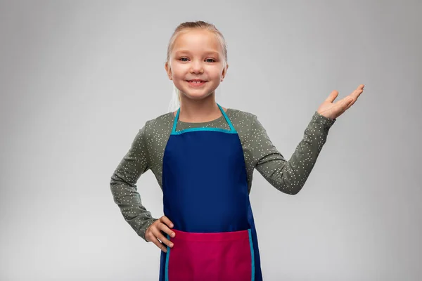 Liten flicka i förkläde håller något på handen — Stockfoto