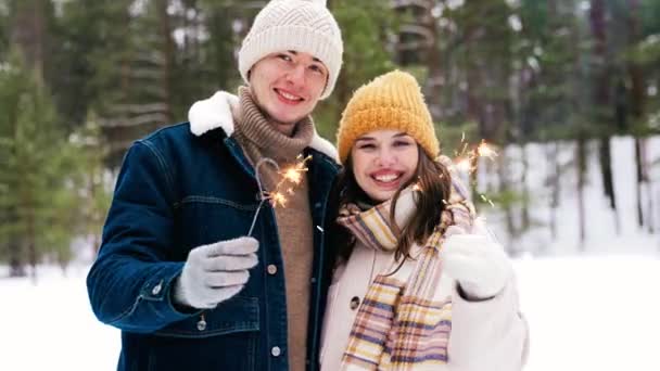 Happy couple with sparklers in winter forest — Stock Video