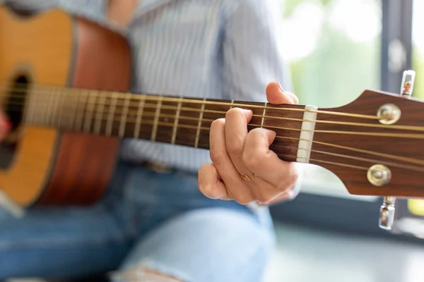 Крупным планом женщина, играющая на гитаре, сидящая на сиденьях — стоковое фото