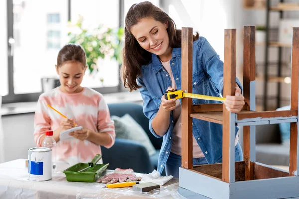 Mother and daughter with ruler measuring old table — Stock Photo, Image