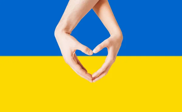 Mani che mostrano la forma del cuore sopra la bandiera dell'Ucraina — Foto Stock