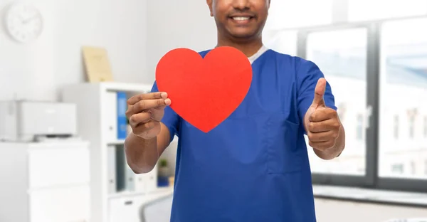 Mężczyzna lekarz z czerwonym sercem pokazuje kciuki w górę — Zdjęcie stockowe