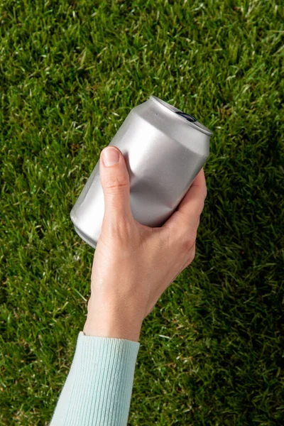 Close up of hand removing used tin can from grass — Stok Foto