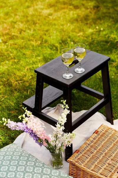 Kosz piknikowy, kwiaty i kieliszki do wina w parku — Zdjęcie stockowe