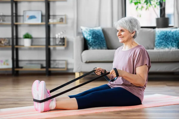 Mujer mayor haciendo ejercicio con banda elástica en casa — Foto de Stock