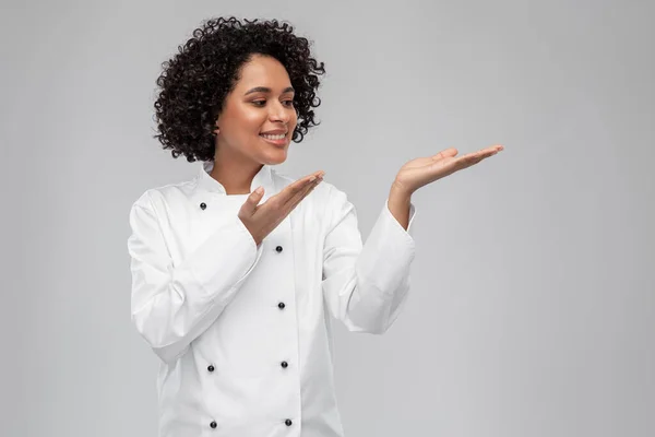 Smiling female chef holding something on hand — Stock Photo, Image