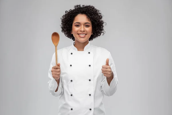 Cocinera sonriente con cuchara mostrando los pulgares hacia arriba —  Fotos de Stock