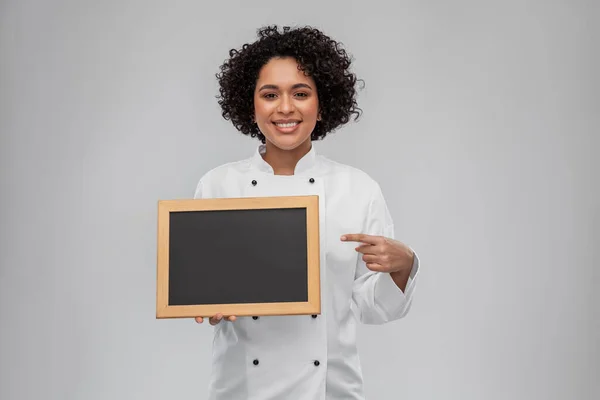Sorridente chef feminino segurando quadro preto — Fotografia de Stock