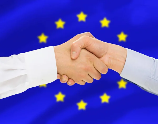 Close up de aperto de mão sobre a bandeira da união europeia — Fotografia de Stock