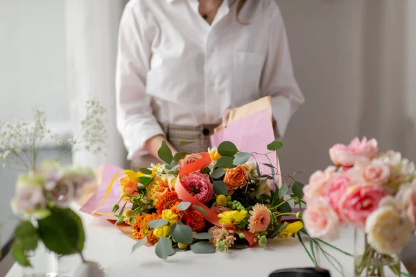 Mujer envolviendo flores a papel artesanal en el estudio — Foto de Stock