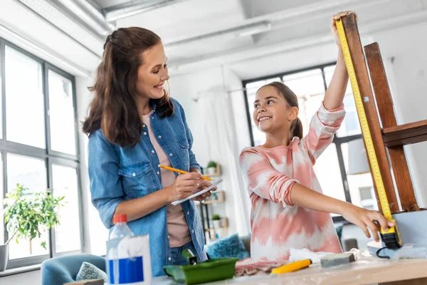 Madre e hija con regla midiendo mesa vieja —  Fotos de Stock