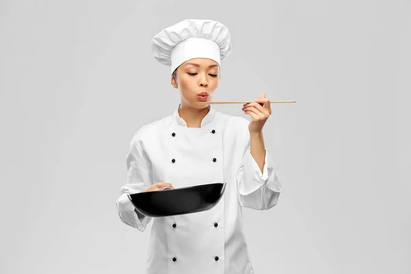 Female chef with frying pan tasting food — Stock Photo, Image