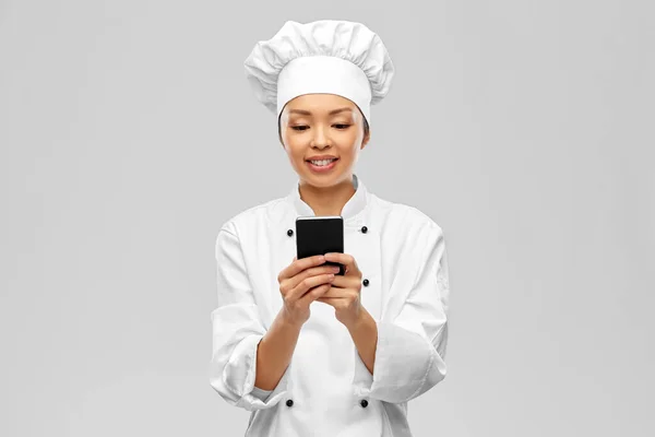 Glimlachende vrouwelijke chef met smartphone — Stockfoto