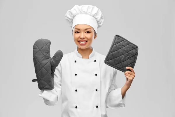 Chef mujer sonriente en chaqueta con agarraderas —  Fotos de Stock