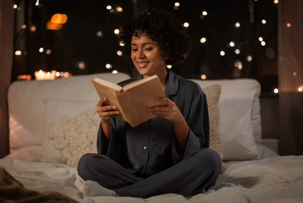 Geceleri yatakta kitap okuyan mutlu bir kadın. — Stok fotoğraf
