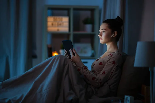 Gadis remaja dengan tablet pc dan earphone di tempat tidur — Stok Foto