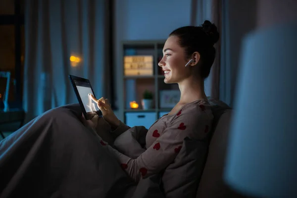Adolescente con tablet pc y auriculares en la cama — Foto de Stock