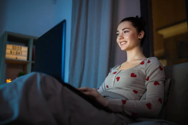 Gadis remaja dengan laptop di tempat tidur di rumah di malam hari — Stok Foto