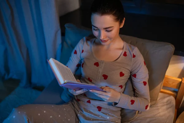 Feliz adolescente leyendo libro en la cama en casa — Foto de Stock