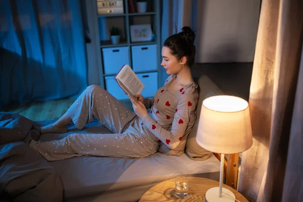 Девочка-подросток читает книгу в постели дома — стоковое фото