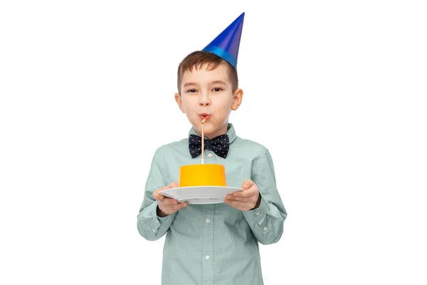 Chlapec v klobouku foukání svíčky na narozeninový dort — Stock fotografie