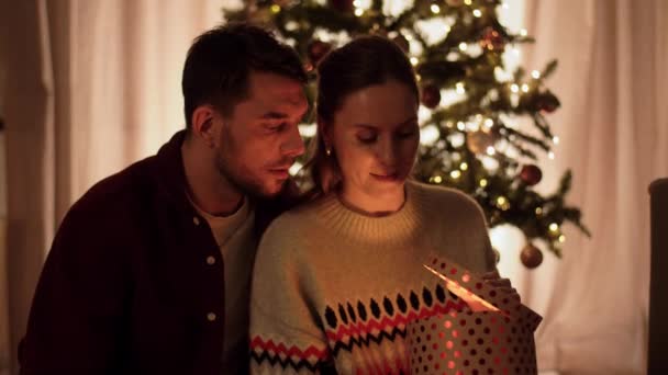 Feliz pareja abriendo mágico regalo de Navidad en casa — Vídeos de Stock