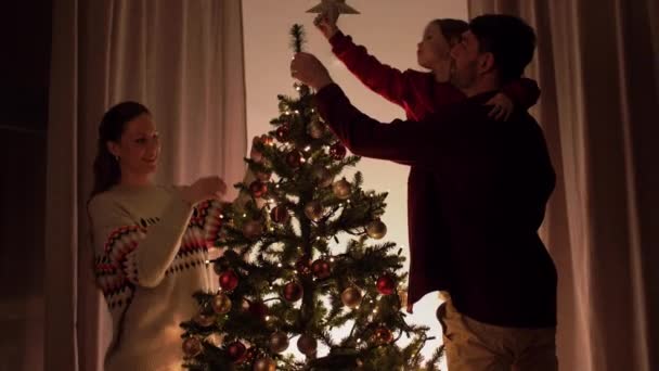 Ευτυχισμένη οικογένεια διακόσμηση χριστουγεννιάτικο δέντρο στο σπίτι — Αρχείο Βίντεο