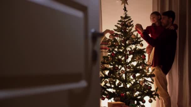 Lycklig familj dekorera julgran hemma — Stockvideo