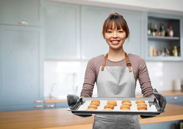 Hembra feliz en delantal con galletas en la bandeja del horno —  Fotos de Stock