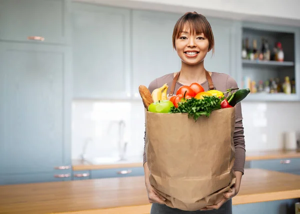 Mujer feliz con comida en bolsa de papel en la cocina —  Fotos de Stock