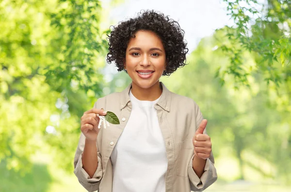 Woman holding house keys with green leaf — Stock Photo, Image