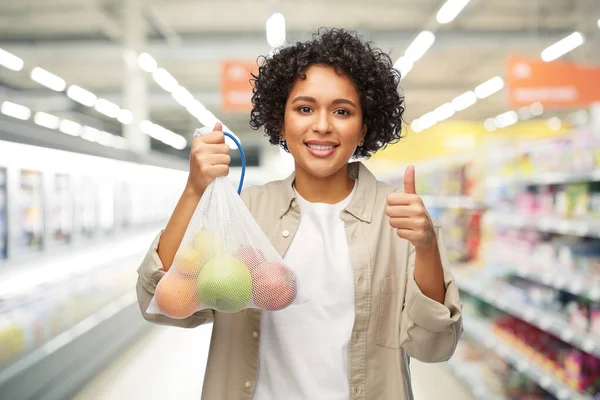 Lycklig kvinna med frukt i återanvändbar sträng väska — Stockfoto