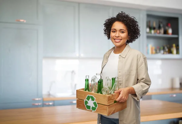 Счастливая женщина с бутылками сортировки отходов стекла — стоковое фото