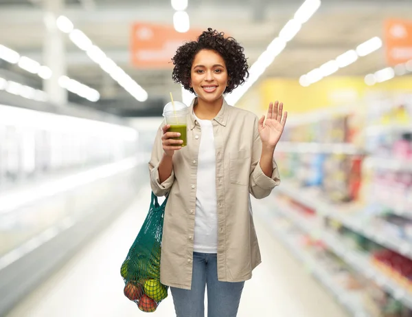 Kobieta z torbą na zakupy wielokrotnego użytku picie smoothie — Zdjęcie stockowe