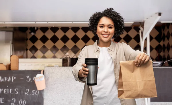 Femme heureuse avec thermotasse et nourriture dans un sac en papier — Photo
