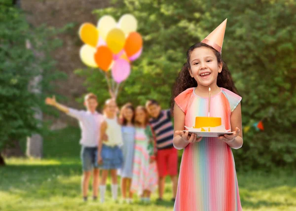 Smiling girl with birthday cake at party in park — Stock Photo, Image