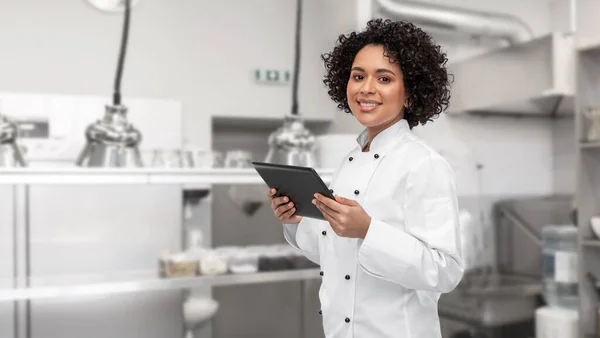 Улыбающаяся женщина шеф-повар показывает планшет ПК на кухне — стоковое фото