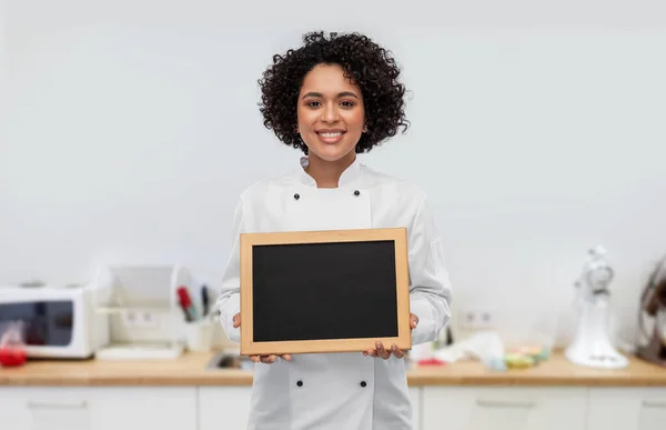 Chef donna sorridente che tiene la lavagna sulla cucina — Foto Stock