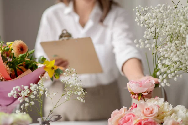 Femme heureuse avec presse-papiers et fleurs au studio — Photo