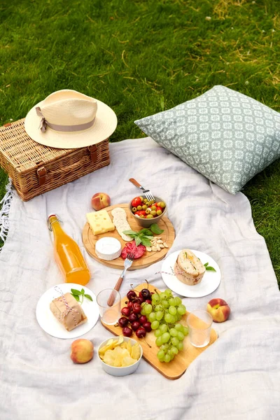 Essen, Getränke und Picknickkorb auf Decke im Gras — Stockfoto