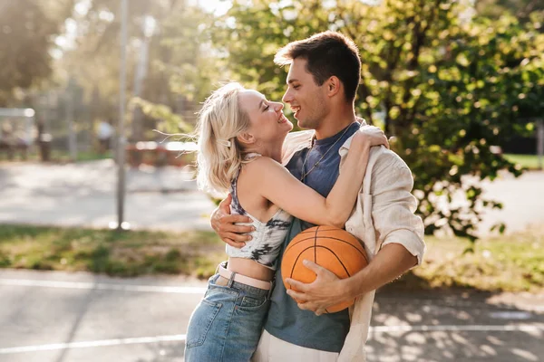 Coppia felice con palla sul campo da basket — Foto Stock
