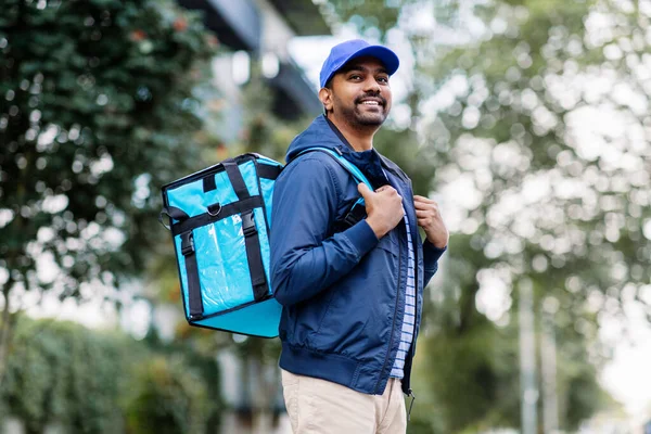 Happy smiling indian delivery man with bag in city — Stock Photo, Image