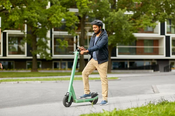 Hombre con smartphone y scooter eléctrico en la ciudad —  Fotos de Stock