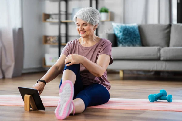 Ευτυχισμένη γυναίκα με tablet pc άσκηση στο σπίτι — Φωτογραφία Αρχείου